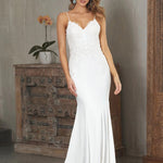 A woman standing in a room wearing a white, V-neck Crepe Fit and Flare Wedding Dress with a plunging back.