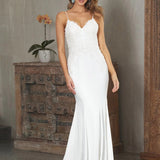A woman standing in a room wearing a white, V-neck Crepe Fit and Flare Wedding Dress with a plunging back.