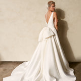 Back view of textured Mikado A-line wedding dress with deep V-back, detachable bow detail, and flowing chapel train.
