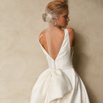 Close-up back view of textured Mikado A-line wedding dress with deep V-back, detachable bow, and bridal birdcage veil.