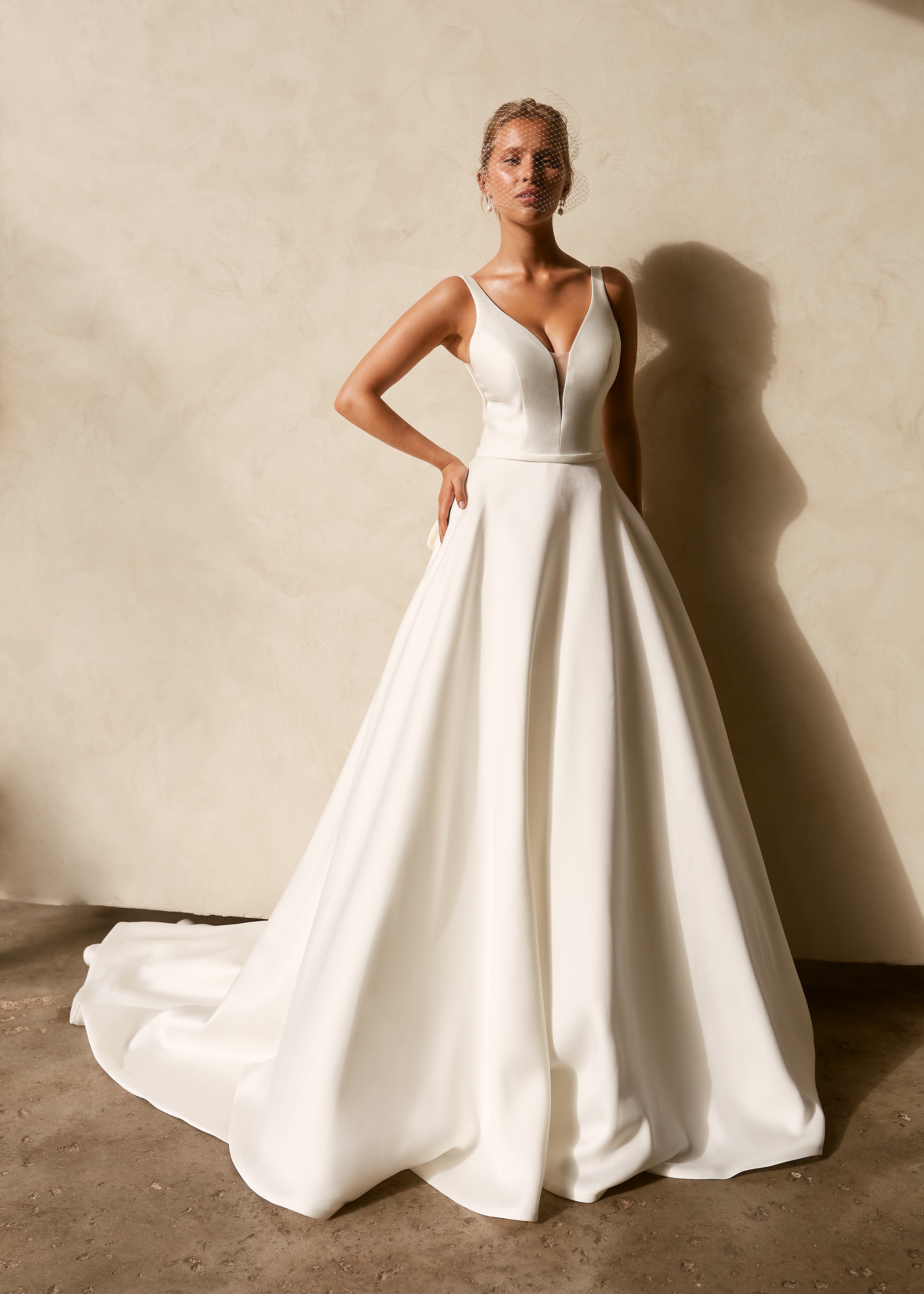Textured Mikado A-line wedding dress with deep V neckline, structured bodice, and flowing chapel train.
