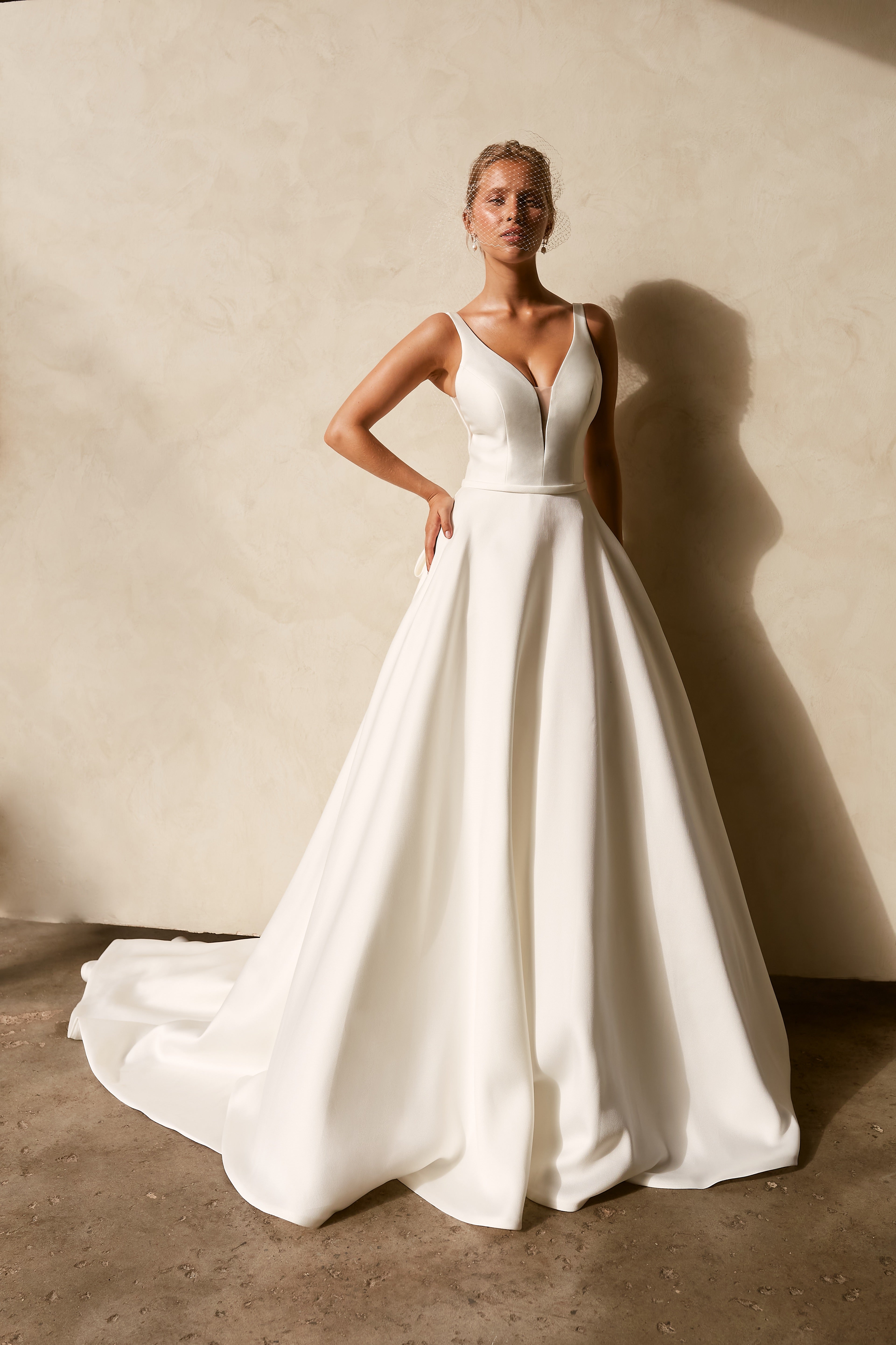 Textured Mikado A-line wedding dress with deep V neckline, structured bodice, and flowing chapel train.

