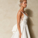 Side view of textured Mikado A-line wedding dress with deep V neckline, structured bodice, and detachable bow detail.
