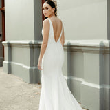 Back view of crepe fit and flare wedding dress with deep V-back, delicate lace bodice detailing, and flowing train.