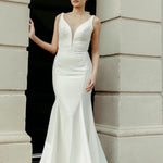 Crepe fit and flare wedding dress with soft V neckline, delicate lace detailing on the bodice, and flowing train.
