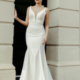 Crepe fit and flare wedding dress with soft V neckline, delicate lace detailing on the bodice, and flowing train.