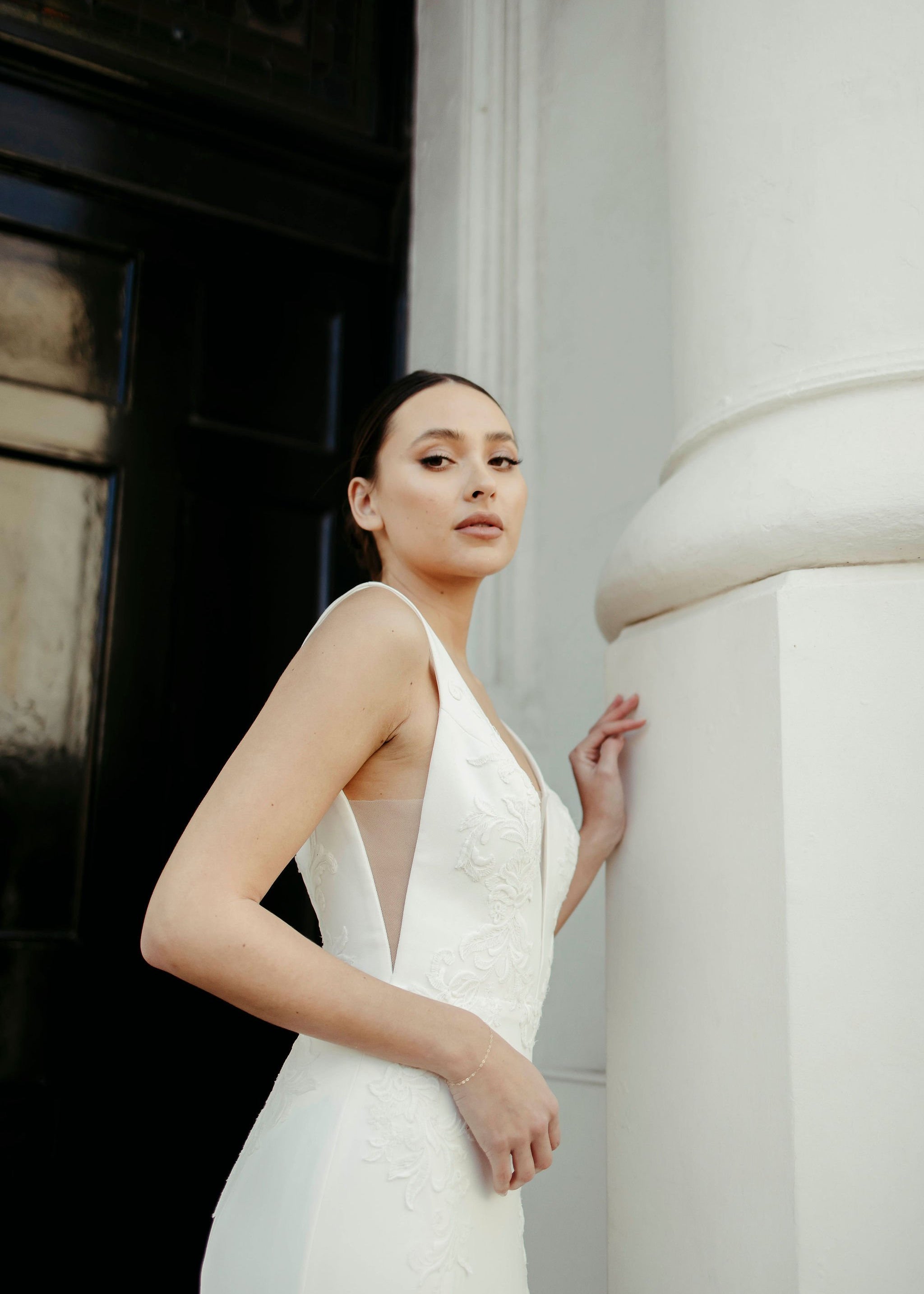 Side view of crepe fit and flare wedding dress with illusion plunge neckline, lace bodice detailing, and sleek silhouette.