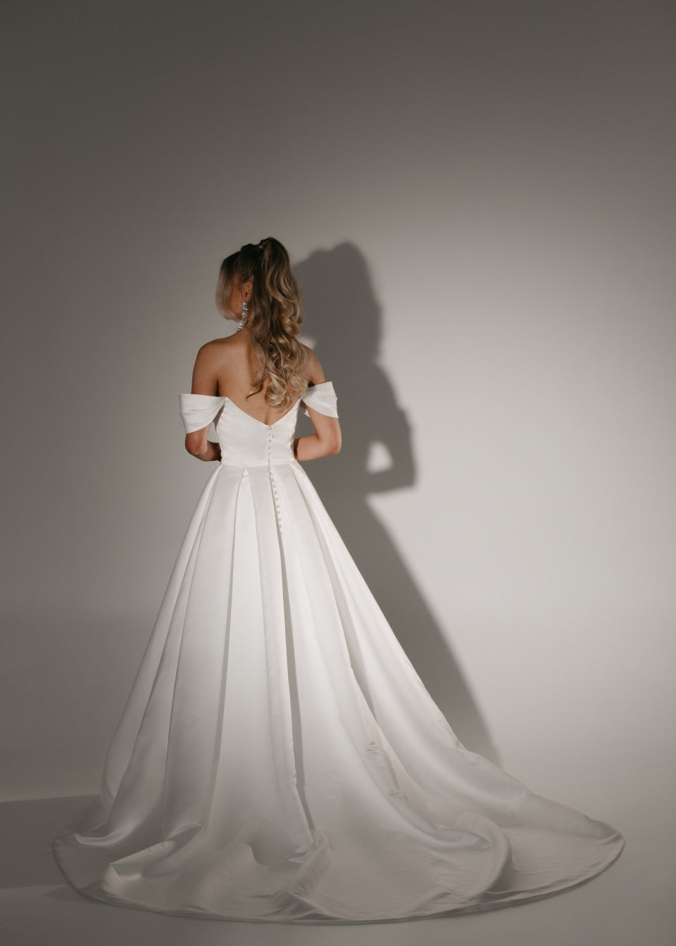 Soulmate off-shoulder wedding dress back view with button detail and full A-line skirt with train.