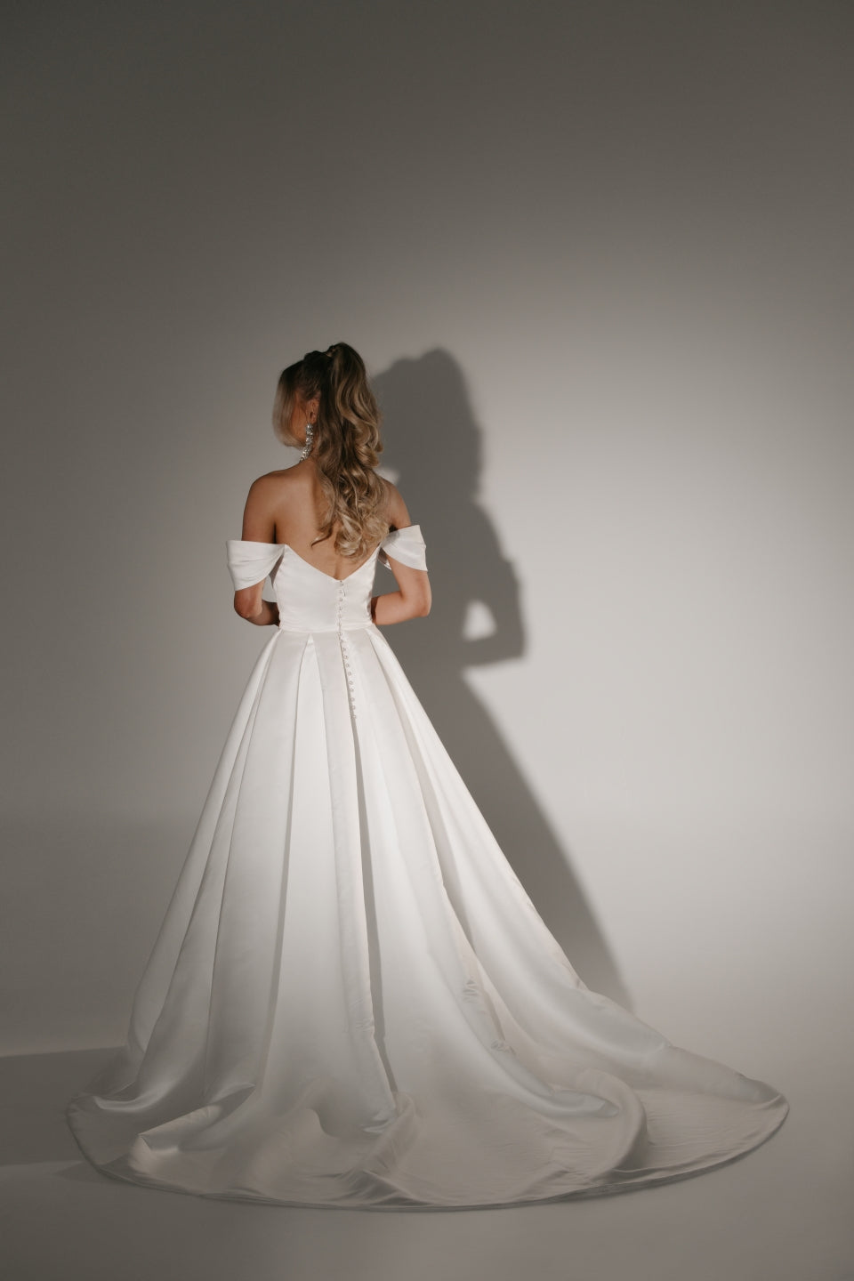 Soulmate off-shoulder wedding dress back view with button detail and full A-line skirt with train.
