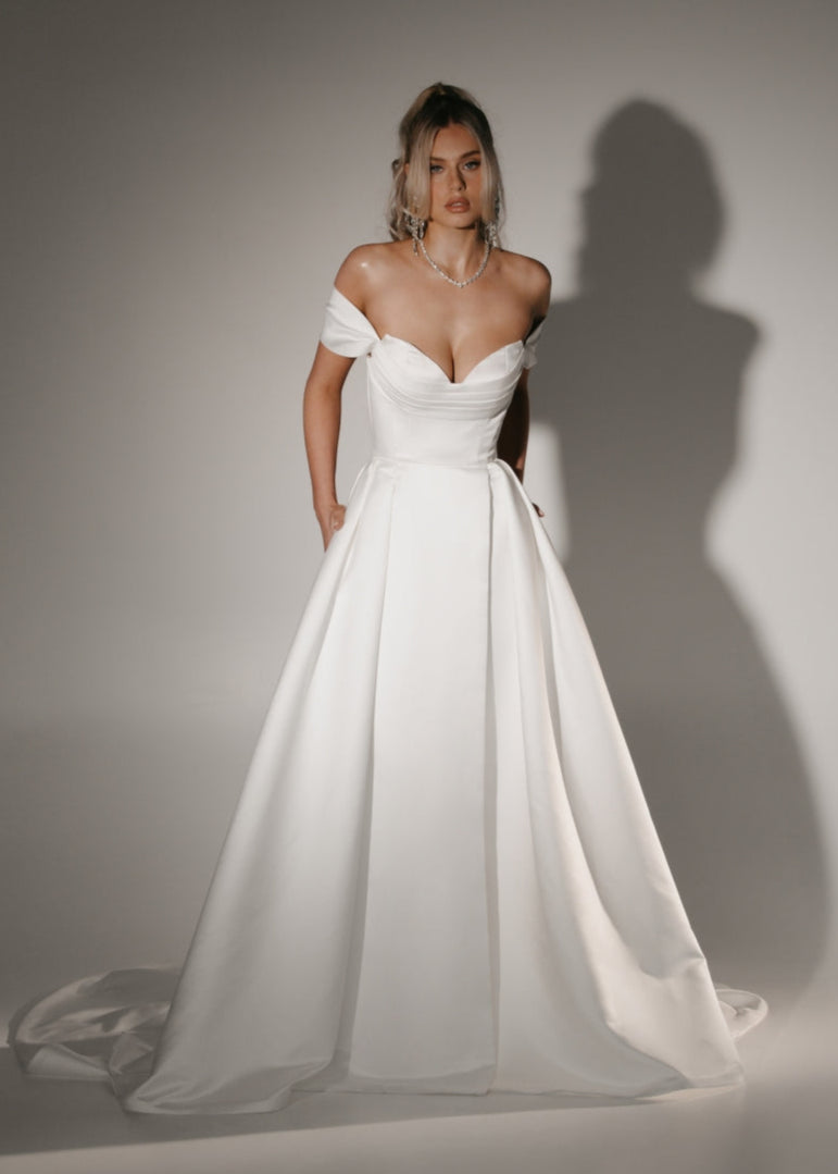 Soulmate off-shoulder wedding dress with draped sweetheart bodice and full A-line skirt.