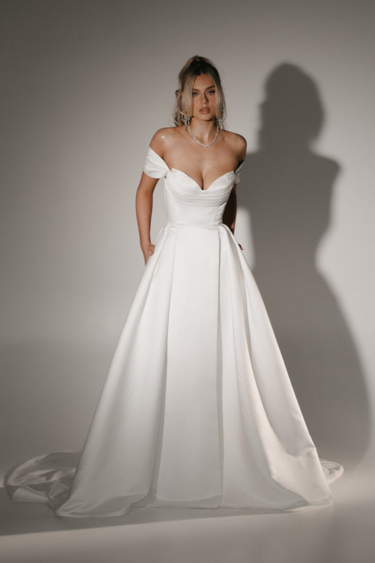 Soulmate off-shoulder wedding dress with draped sweetheart bodice and full A-line skirt.