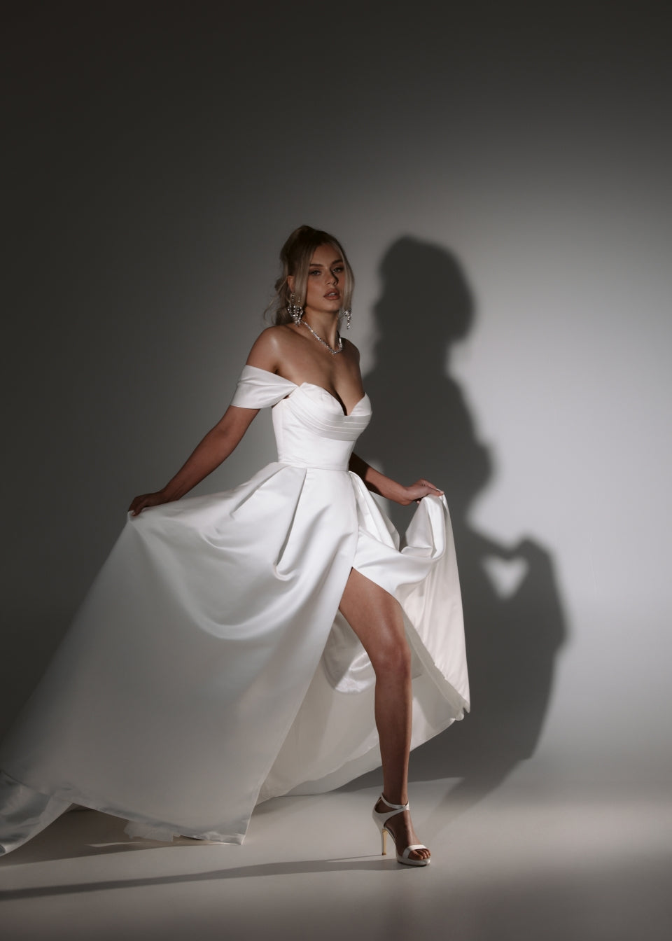 Soulmate off-shoulder wedding dress with draped bodice, high leg split and flowing A-line skirt.