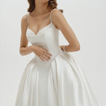Woman wearing a basque waist Mikado ballgown wedding dress against a plain background