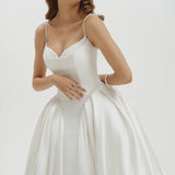 Woman wearing a basque waist Mikado ballgown wedding dress against a plain background