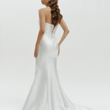 Woman wearing a strapless liquid organza fitted wedding dress on a white background