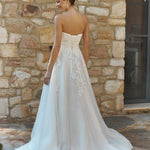 Woman in a Lace A-Line Wedding Dress standing against a stone wall.