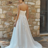 Woman in a Lace A-Line Wedding Dress standing against a stone wall.