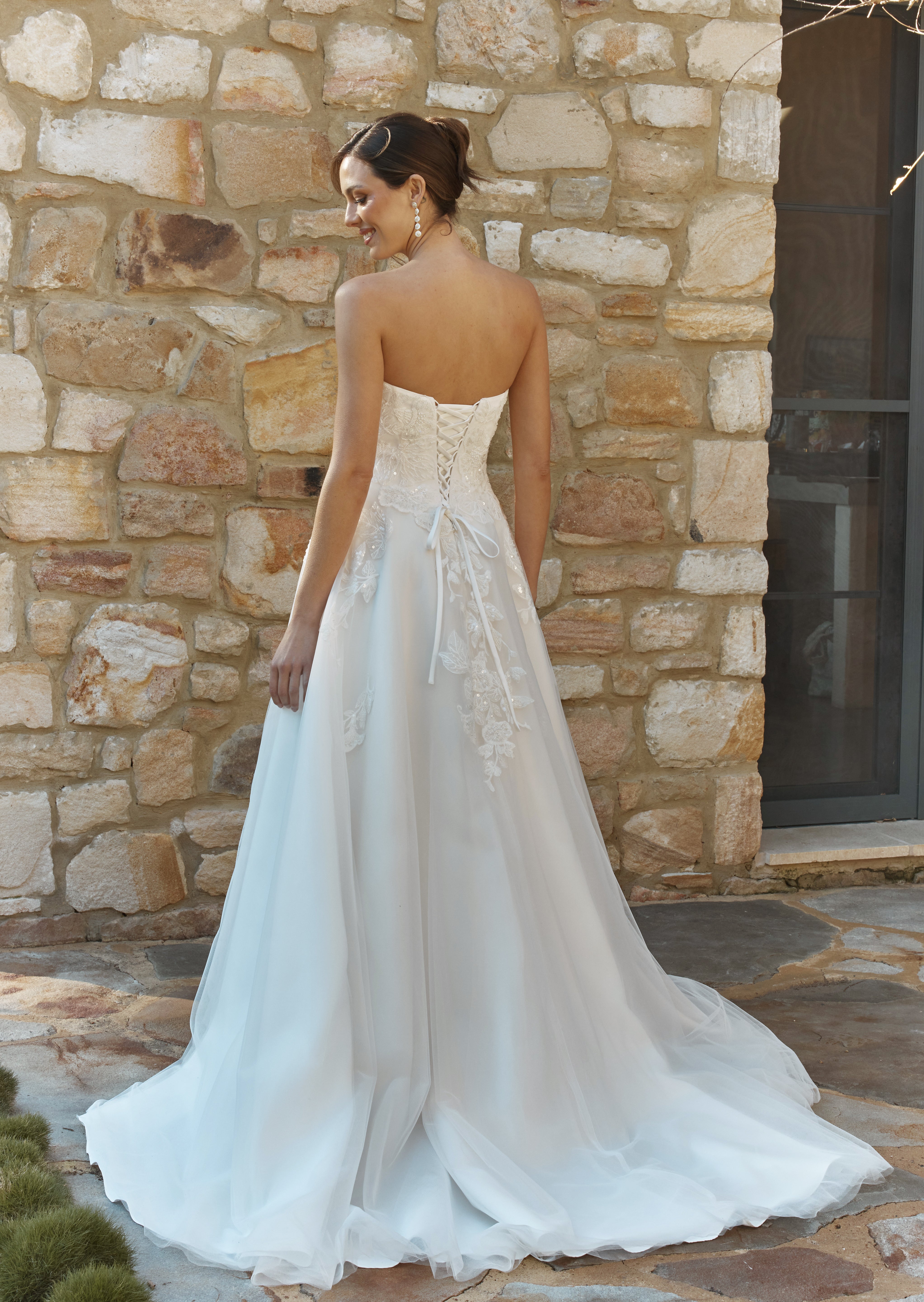 Woman in a Lace A-Line Wedding Dress standing against a stone wall.
