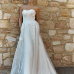 Woman in a Lace A-Line Wedding Dress standing against a stone wall.
