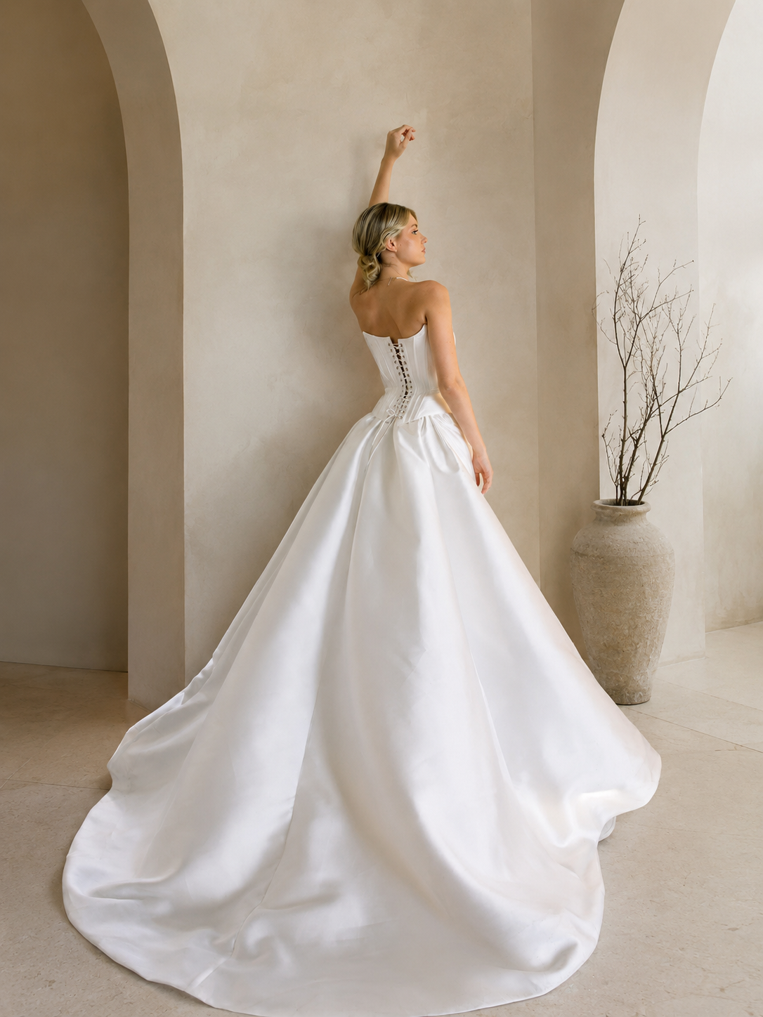 Woman in a Modern Mikado Wedding Dress standing in a modern indoor setting with concrete walls and natural light.