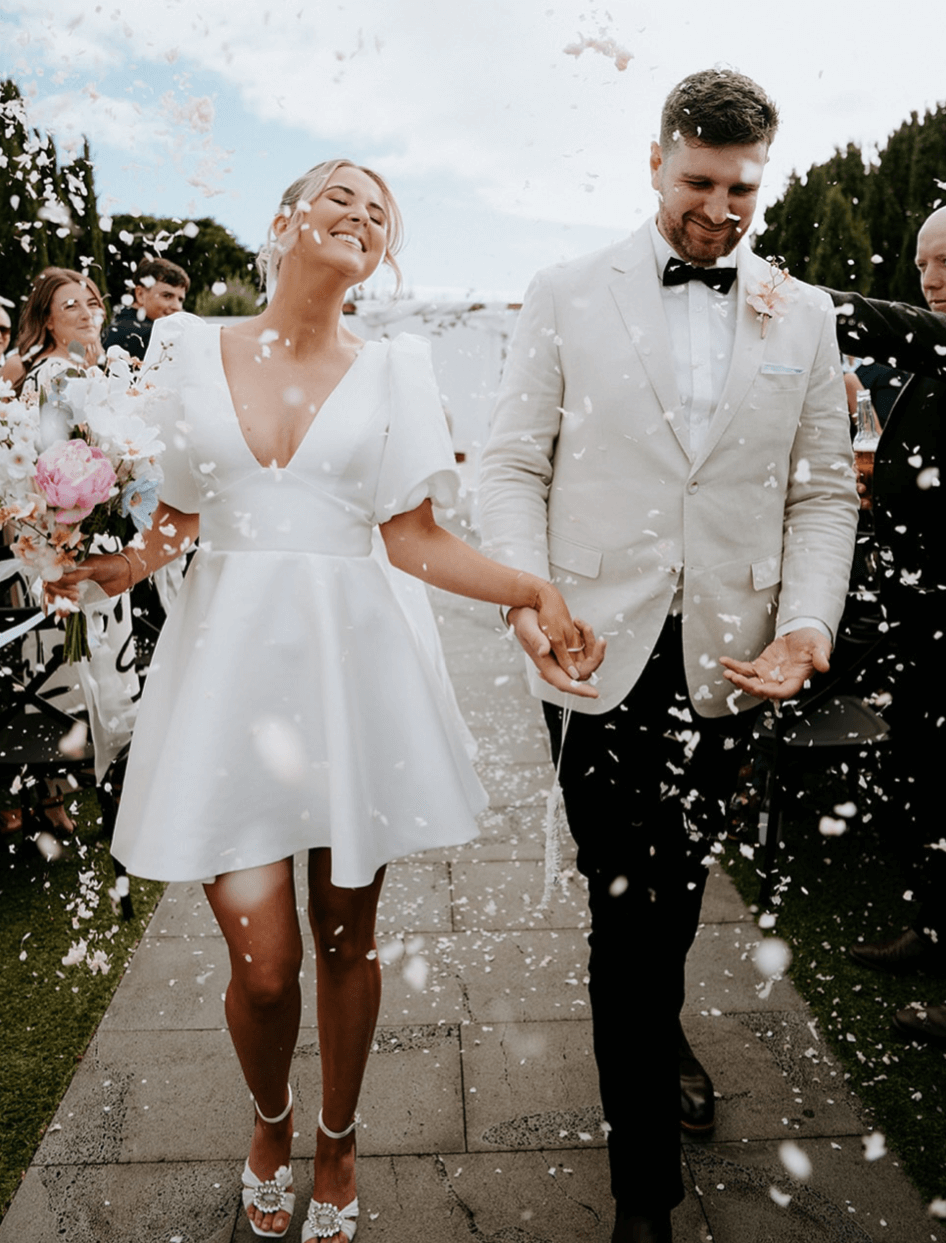 Belle Mini wedding dress in at wedding ceremony featuring short A-line silhouette and puff sleeves