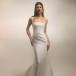 Bride wearing the Bellevue modern fitted wedding dress with thin straps and draped bodice, photographed against a soft studio background.
