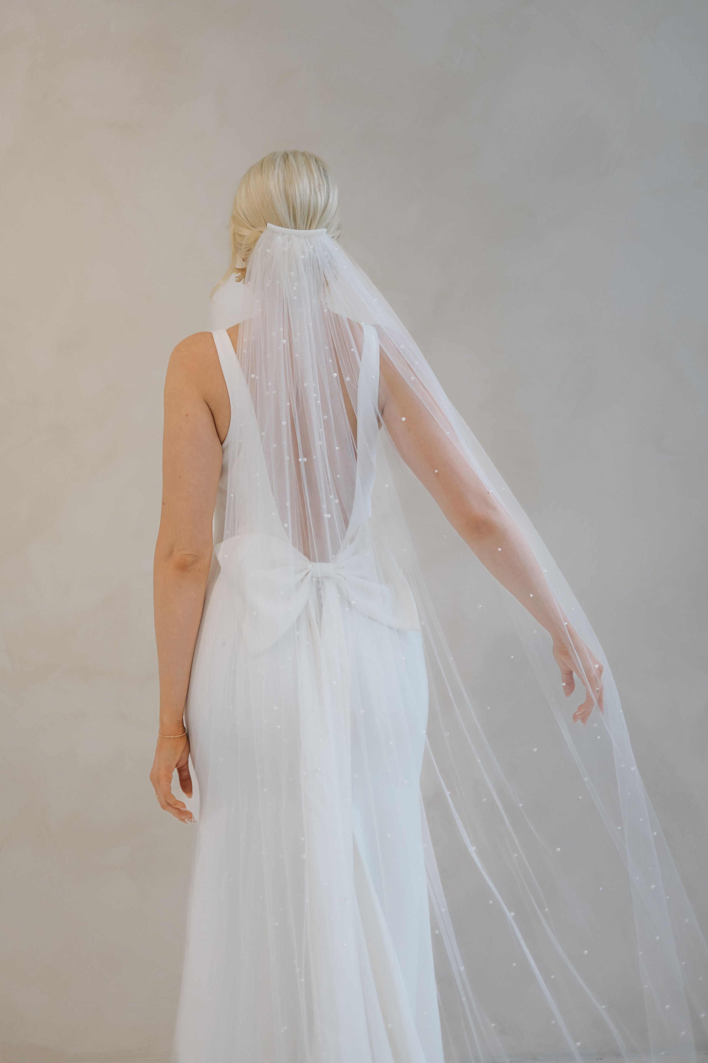 Back of a bride wearing a veil and a Crepe Fit and Flare Wedding Dress