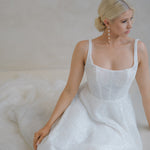 Bride sitting on the floor in a Beaded A-Line Wedding Dress in front of a neutral back drop 