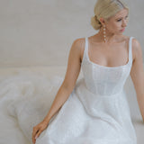 Bride sitting on the floor in a Beaded A-Line Wedding Dress in front of a neutral back drop 