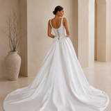 back view of a bride wearing a satin A-line wedding dress with square neckline in a garden