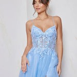 Woman wearing a light blue evening gown with lace details against a plain background