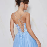 Woman wearing a light blue dress with a criss-cross back design on a plain background