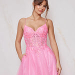 Woman wearing a pink evening gown with floral lace details on a light background