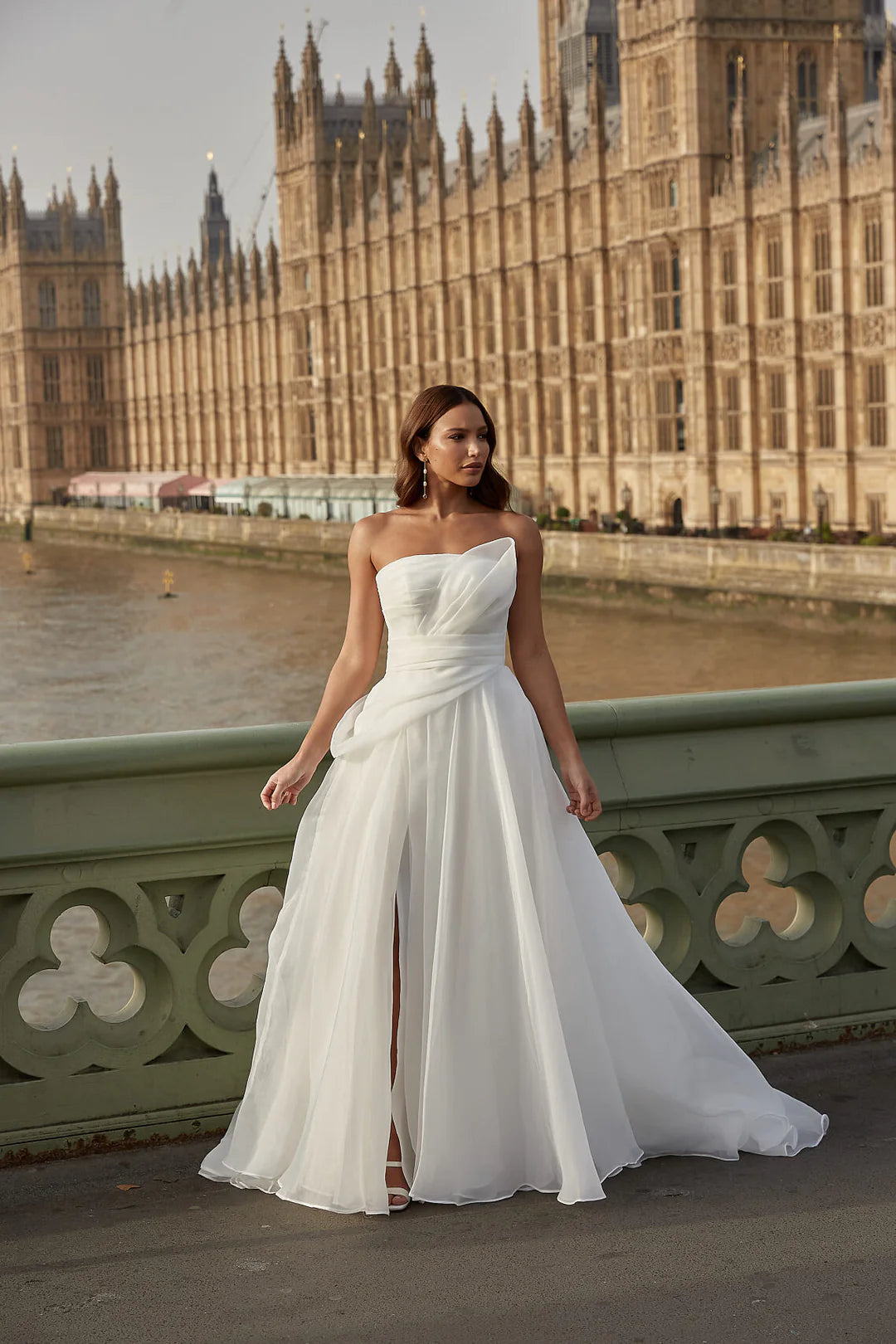 Woman in a organza A-line wedding dress standing on a bridge with the Houses of Parliament in the background.
