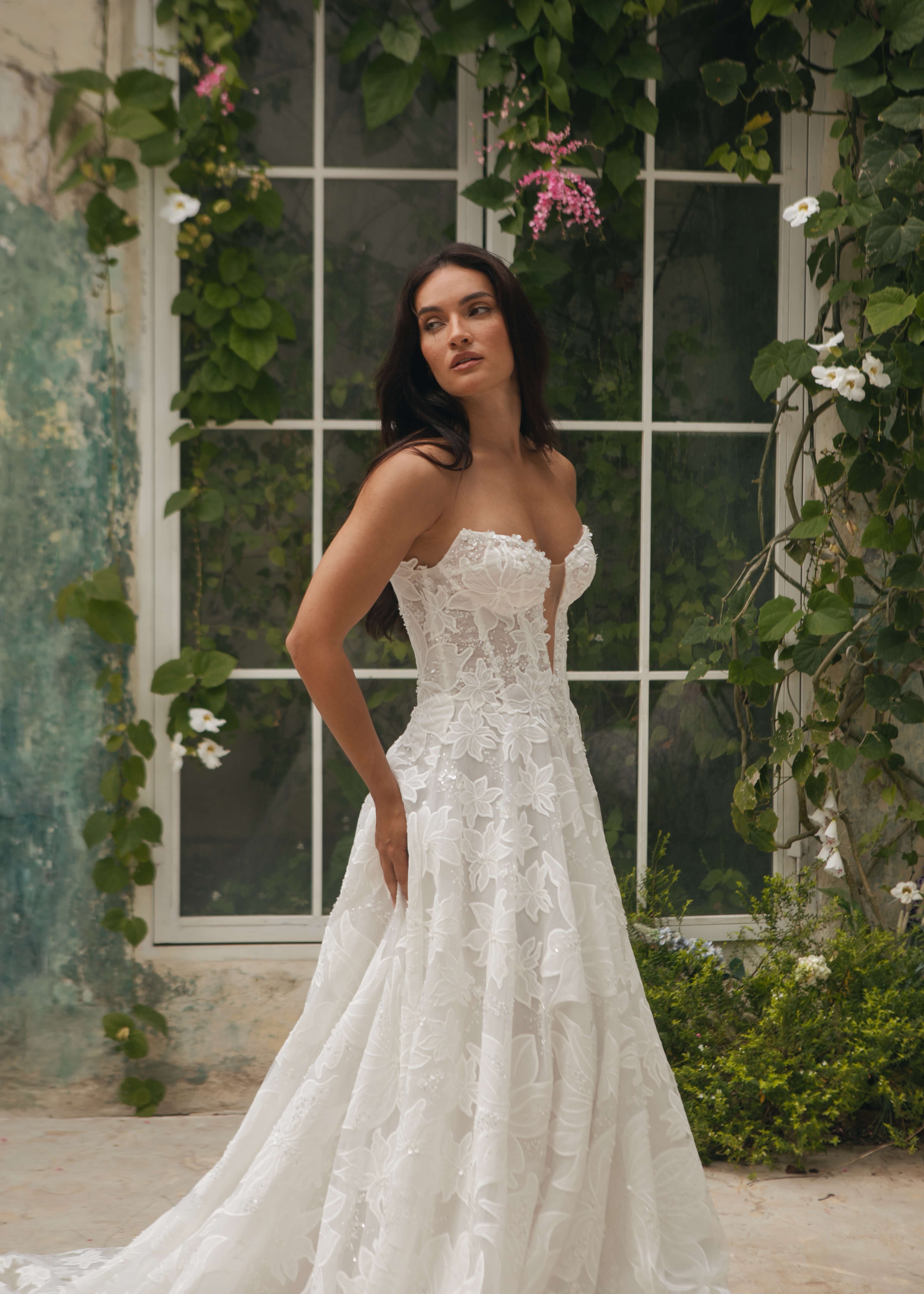 Woman in a white Lace A-Line Wedding Dress standing in front of a window with greenery.