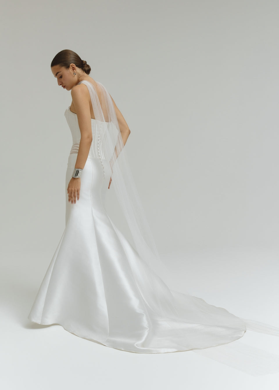 Woman wearing a dropped waist Mikado fitted wedding dress on a plain background