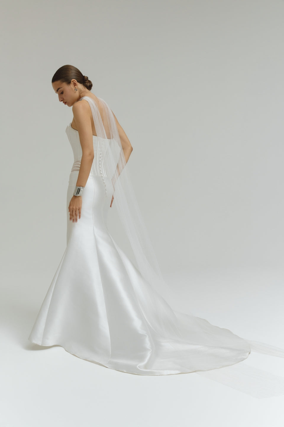 Woman wearing a dropped waist Mikado fitted wedding dress on a plain background
