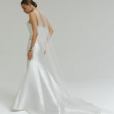 Woman wearing a dropped waist Mikado fitted wedding dress on a plain background