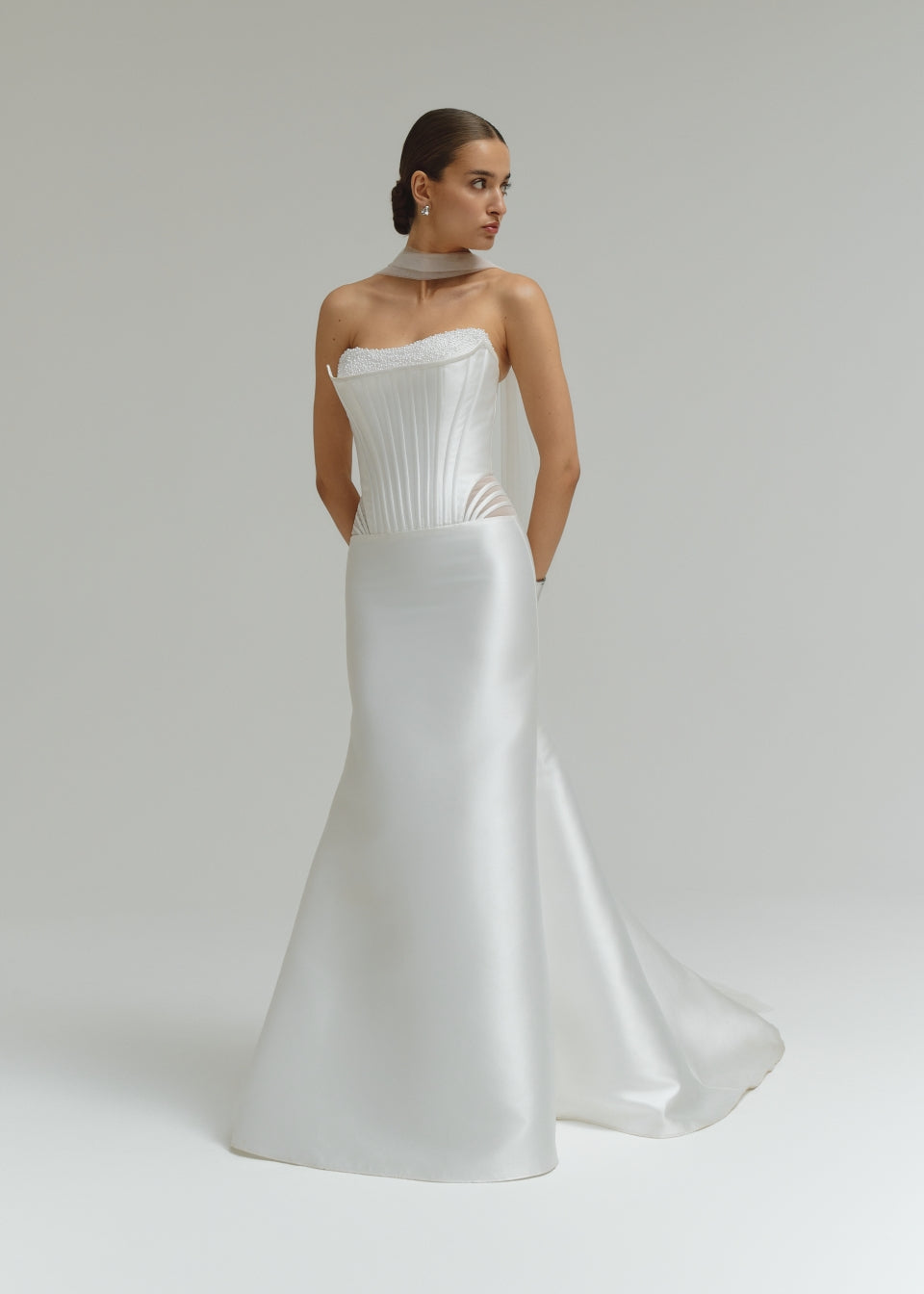 Woman wearing a dropped waist Mikado fitted wedding dress on a plain background