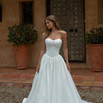 Woman in a Satin A-Line Wedding Dress standing in front of a rustic building.