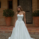 Woman in a Satin A-Line Wedding Dress standing in front of a rustic building.