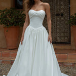 Woman wearing a Satin A-Line Wedding Dress standing outdoors with a rustic background.