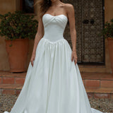 Woman wearing a Satin A-Line Wedding Dress standing outdoors with a rustic background.