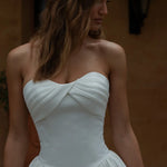 Woman wearing a Satin A-Line Wedding Dress against a warm-toned wall.