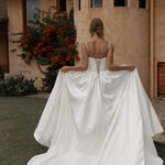 Woman in a Mikado A-Line Wedding Dress standing in front of a building with a garden.
