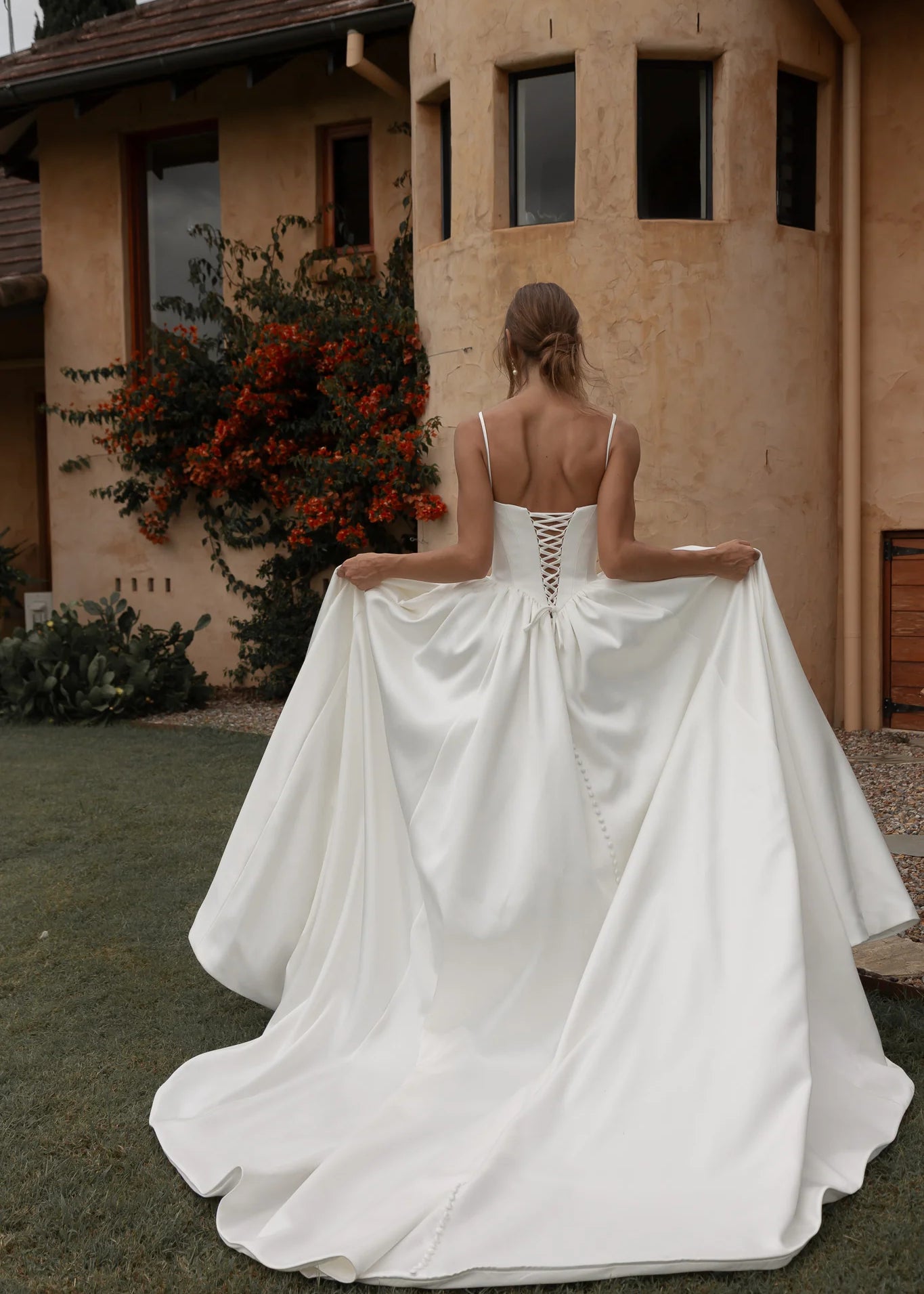 Woman in a Mikado A-Line Wedding Dress standing in front of a building with a garden.