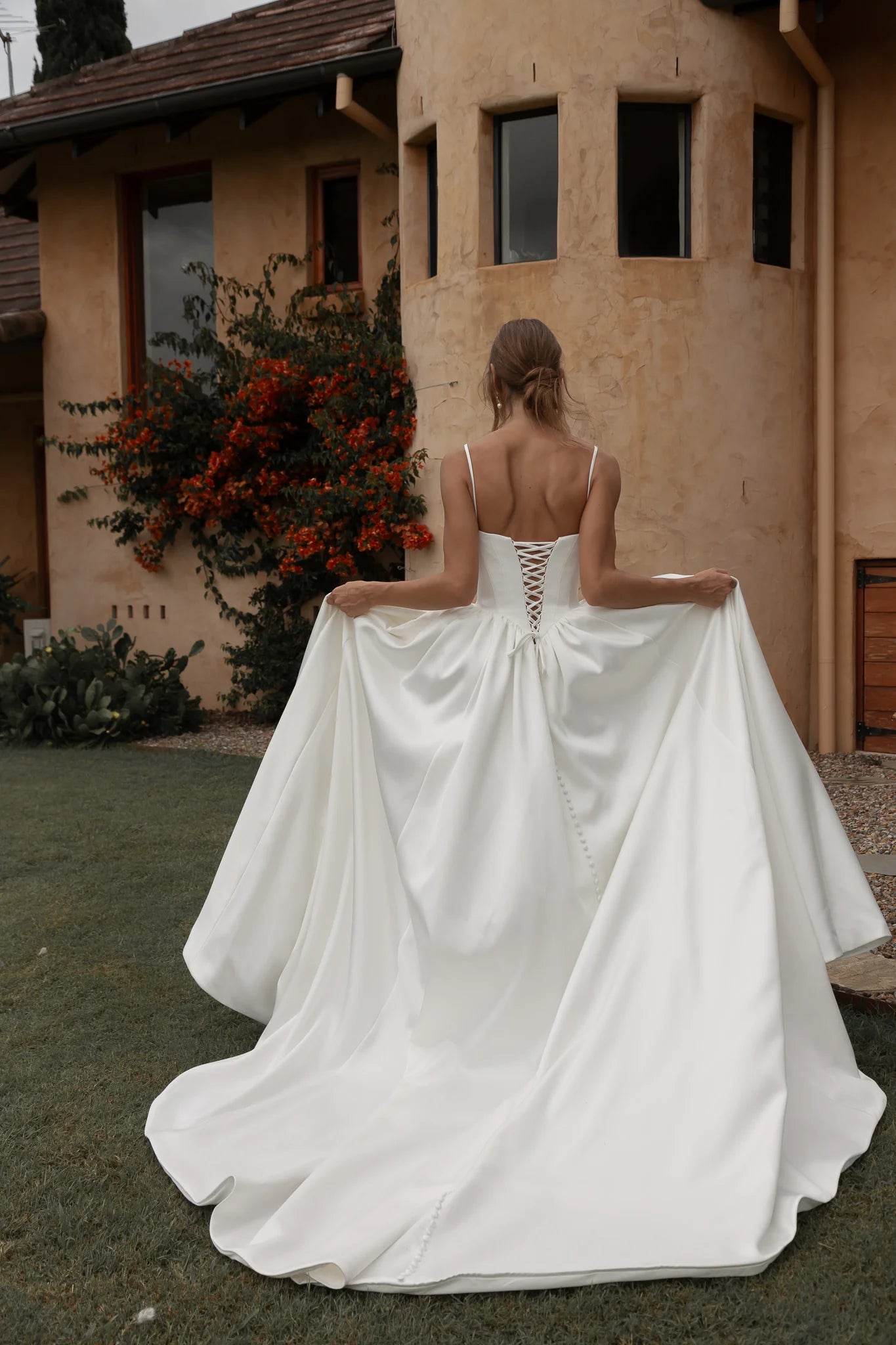 Woman in a Mikado A-Line Wedding Dress standing in front of a building with a garden.