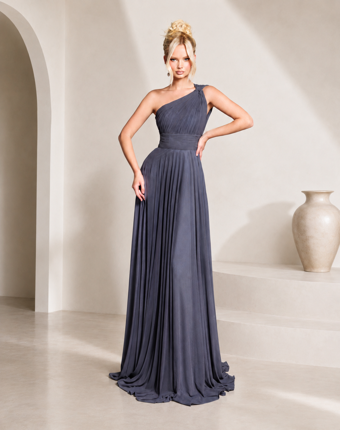 Woman wearing a one-shoulder blue gown in a minimalistic setting