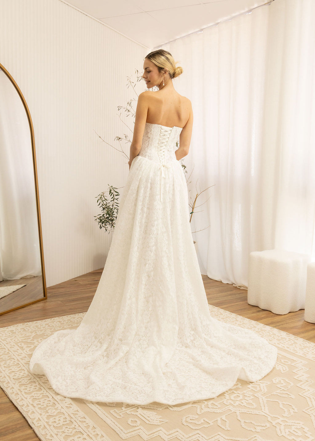 Woman in a Lace Strapless A-Line Wedding Dress standing in a room with white curtains and a wooden floor.