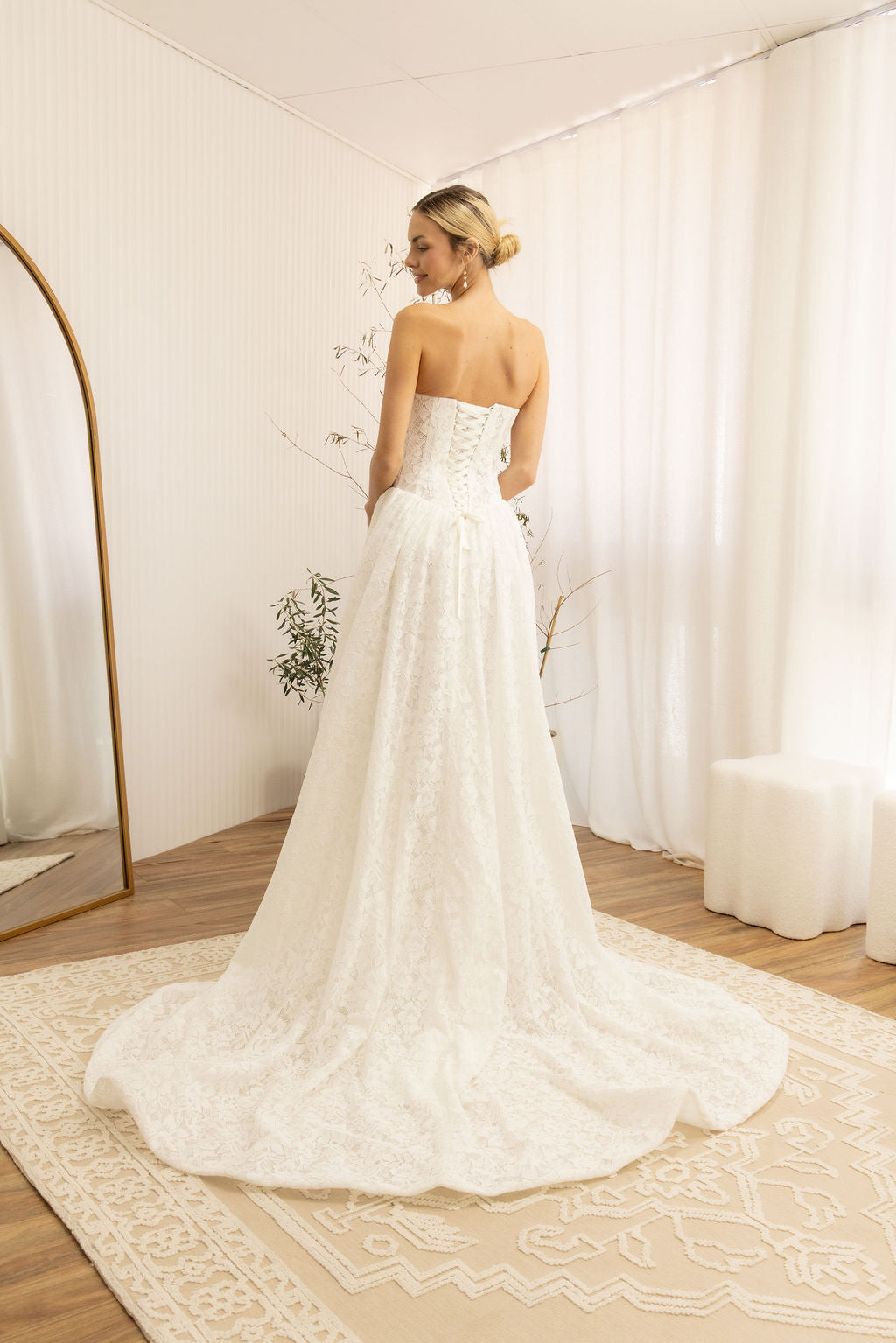 Woman in a Lace Strapless A-Line Wedding Dress standing in a room with white curtains and a wooden floor.